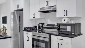 A modern kitchen with stainless steel appliances, a coffee maker, and a microwave. - Crescent Heights Hideout. (Calgary)