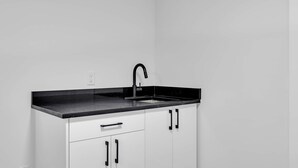 A kitchen with a black countertop, white cabinets, and a black faucet. - Crescent Heights Hideout. (Calgary)