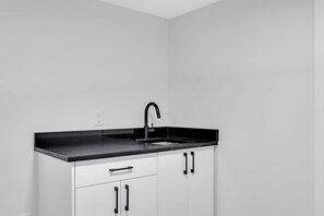 Eine Küche mit schwarzem Arbeitsplatz, weißen Schränken und einem schwarzen Wasserhahn.