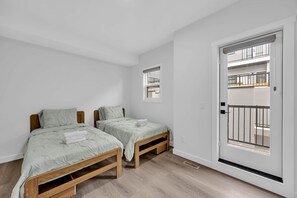Ein Schlafzimmer mit zwei Betten, einem Fenster und einer Tür, die auf einen Balkon führt.