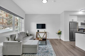 Eine moderne Wohnung mit Wohnbereich, Küche und großen Fenstern.