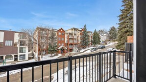 A residential area with multi-story buildings, a snow-covered street, and a clear sky. - Crescent Heights Hideout. (Calgary)