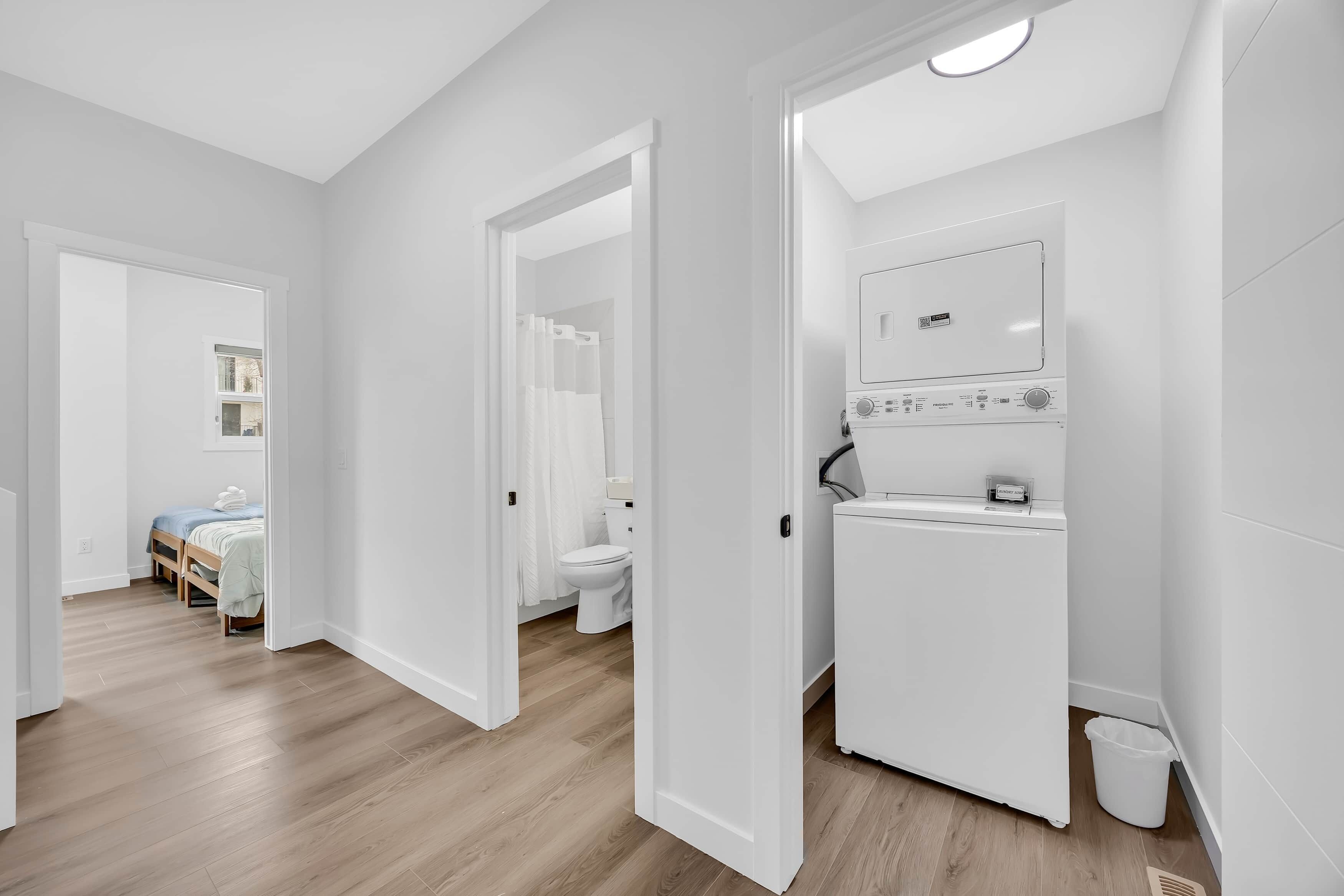 A modern, well-lit room with a wooden floor, a white radiator, and a visible bathroom with a toilet and shower.