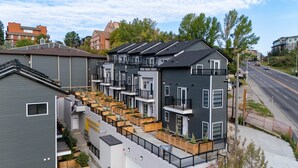 En moderne, flereetagers boligbygning med altaner, en tagterrasse og udsigt til gaden.