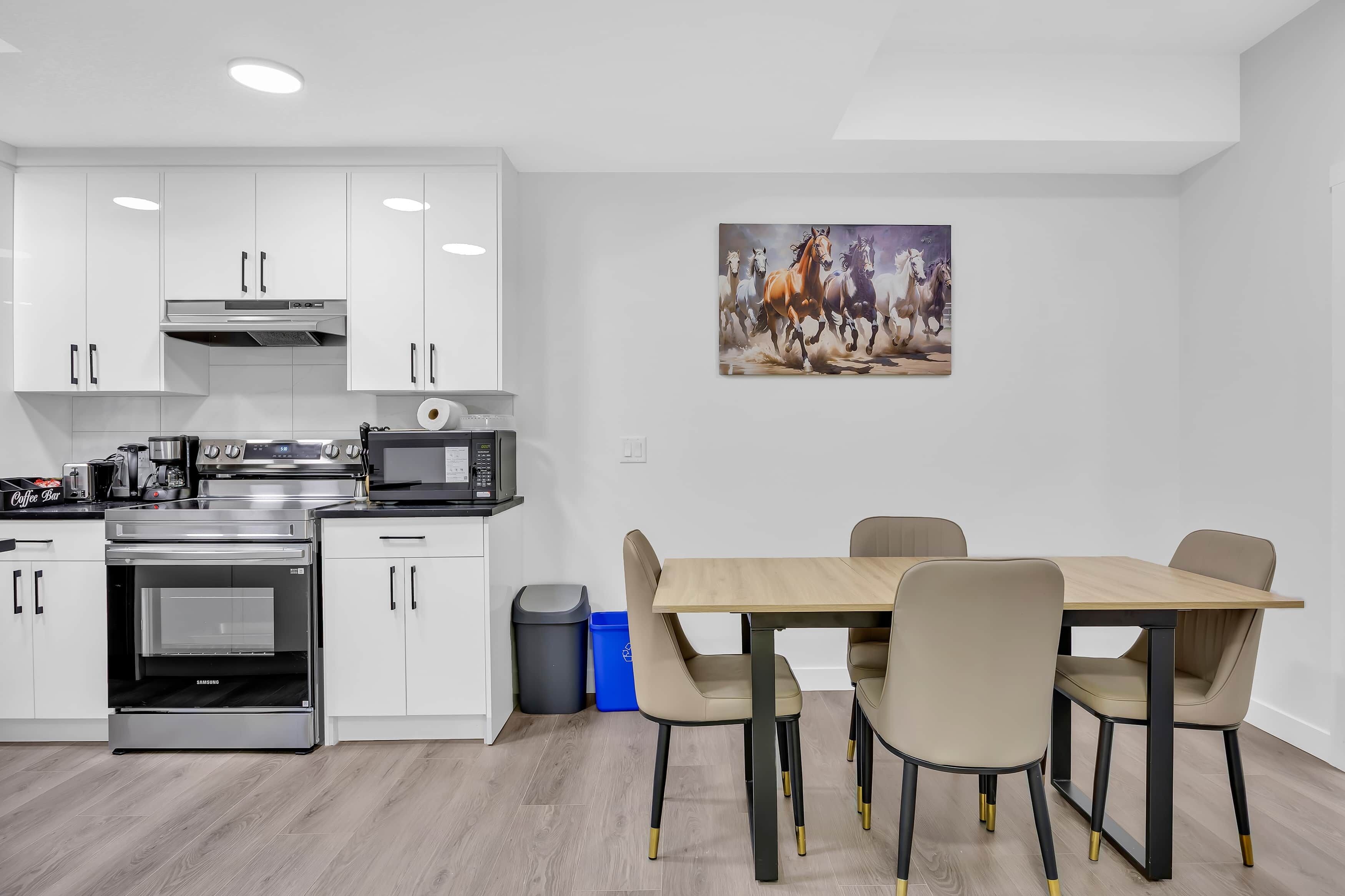 A modern kitchen with white cabinets, a built-in oven, and a dining area with a wooden table and chairs.