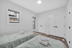 Ein Schlafzimmer mit zwei Betten, einem Fenster, einer Tür und einem Kleiderschrank.