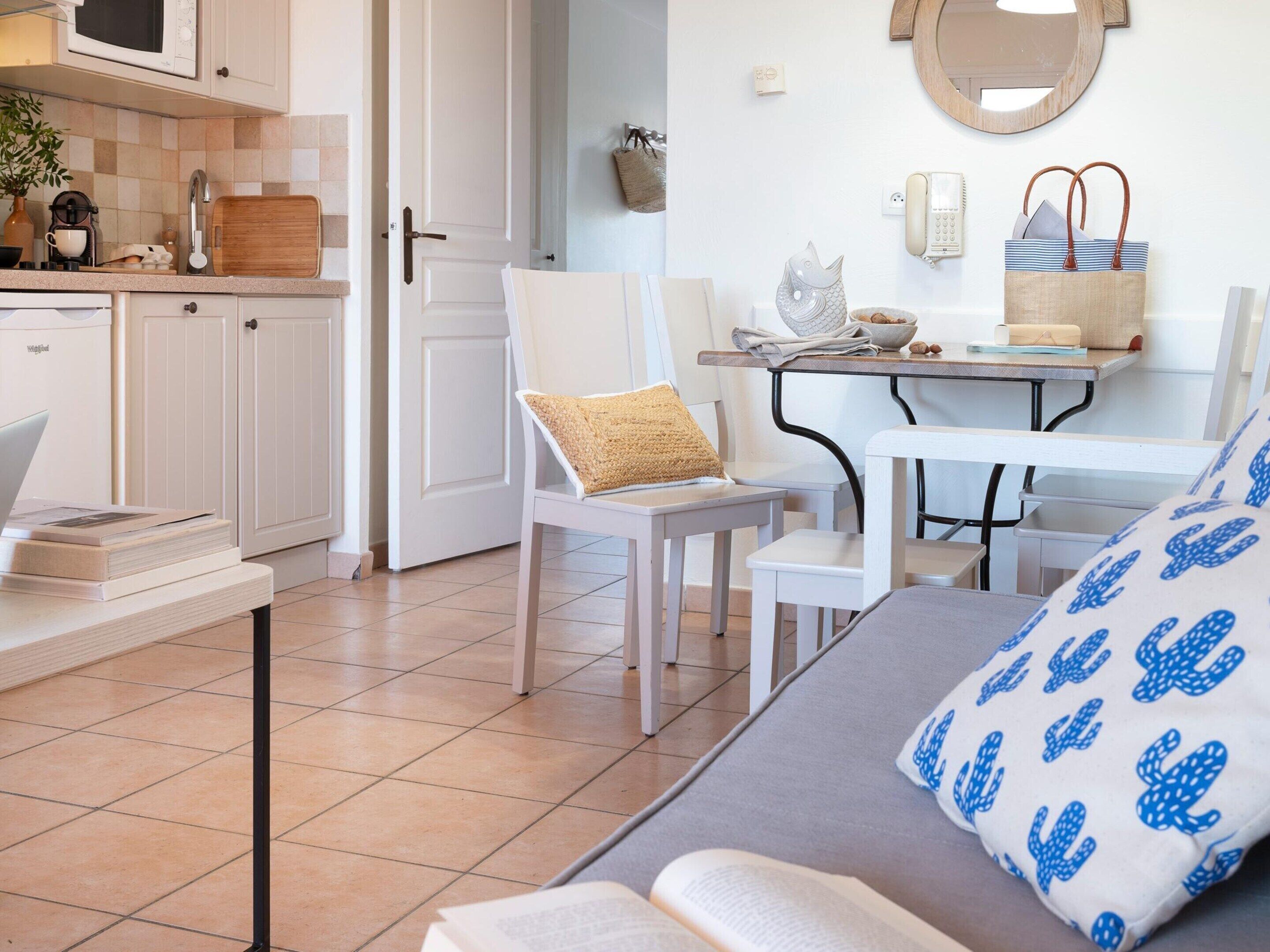 Un espace de vie compact comprenant un coin cuisine, un coin repas et un coin salon avec un canapé et des fauteuils.