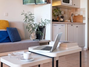 Una sala de estar moderna con un sofá, una mesa de centro con una computadora portátil, una taza y un control remoto.