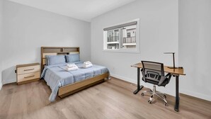 A bedroom with a bed, a desk, and a window. - Work away from home! Crescent Heights. (Calgary)
