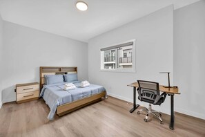 Ein Schlafzimmer mit Bett, Schreibtisch und Fenster.