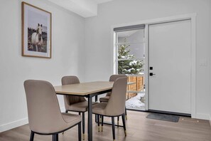 A dining area with a table and four chairs, a framed picture on the wall, and a sliding glass door leading to a snowy outdoor area. - Work away from home! Crescent Heights. (Calgary)