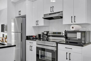 A modern kitchen with stainless steel appliances, a coffee bar, and a microwave. - Work away from home! Crescent Heights. (Calgary)