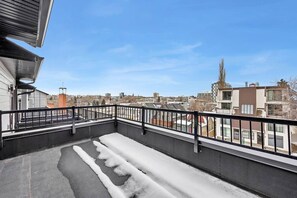 Ein Balkon mit Metallgeländer, Blick auf die Stadtlandschaft und ein Gebäude mit einem Turm.