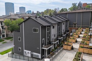 Un immeuble résidentiel à plusieurs étages, doté de balcons, d’un jardin sur le toit et offrant une vue sur la ville.