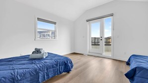 Quarto com duas camas, uma janela e porta de correr.