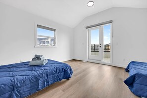 Ein Zimmer mit zwei Betten, einem Fenster und einer Schiebetür.