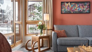 Ein gemütliches Wohnzimmer mit einem grauen Sofa, einem Holztisch mit Blumenvase und einem Schachbrett.