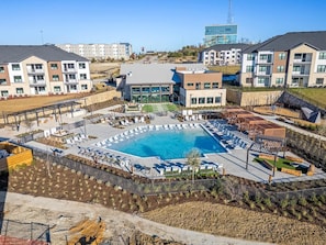 Ein moderner Apartmentkomplex mit einem zentral gelegenen Schwimmbad, Außenbereichen zum Sitzen und einem angelegten Garten.