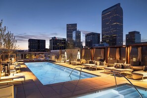 A rooftop pool with lounge chairs and a city skyline in the background. - Landing | Spectacular 1BD, Rooftop Lounge, Gym (Denver)