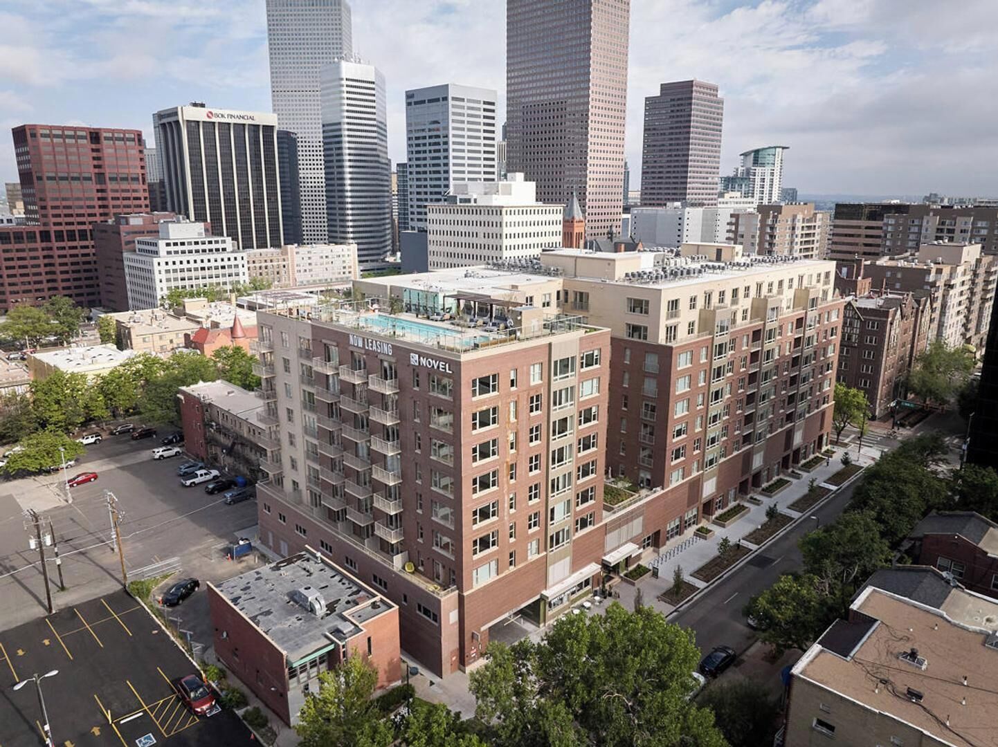 A multi-story building with a rooftop pool, surrounded by other high-rise buildings in an urban setting.