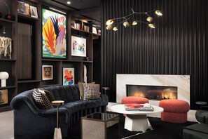 Ein modernes Wohnzimmer mit einem dunkelgrauen Sofa, einem Kamin und einem Bücherregal mit verschiedenen gerahmten Kunstwerken.