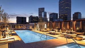 A rooftop pool with lounge chairs and a city skyline in the background. - Landing | Stylish 2BD, Rooftop Lounge, Gym (Denver)