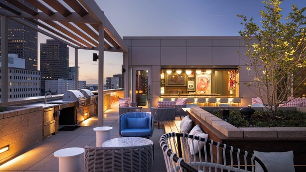 A rooftop terrace with outdoor seating, a bar area, and a grill. - Landing | Stylish 2BD, Rooftop Lounge, Gym (Denver)