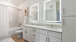 Ein modernes Badezimmer mit Badewanne, Toilette, Waschtisch mit Spiegeln und Schränken.