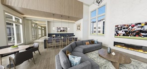 A modern living room with a sectional sofa, a dining area with a bar, and a fireplace. - Landing | Stunning 1BD in Northwest Side (San Antonio)