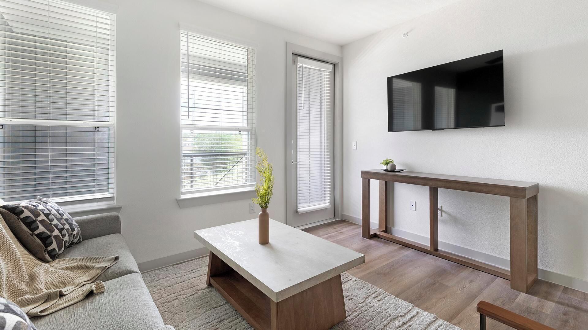 A modern living room with a sofa, coffee table, and a TV mounted on the wall.