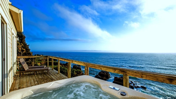 Una terraza de madera con un jacuzzi con vista al océano.