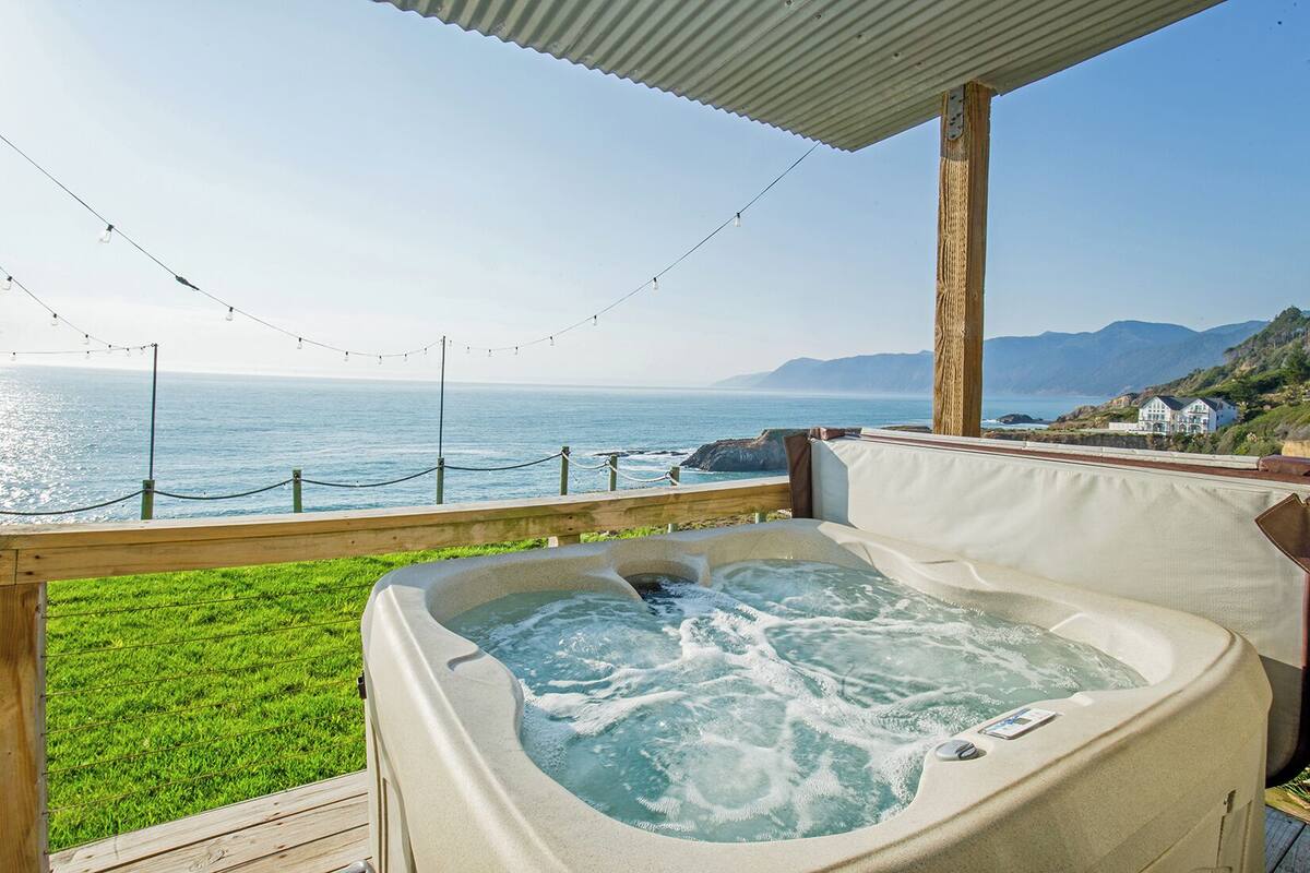 Un jacuzzi con vistas al océano y a las montañas.