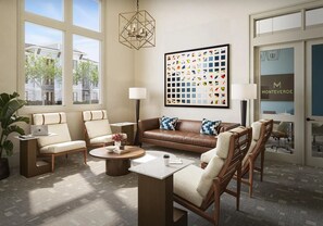Ein modernes Wohnzimmer mit einer braunen Ledersofa, beigen Sesseln, einem Couchtisch und einem großen abstrakten Gemälde.