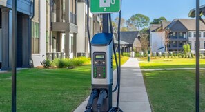 A charging station with a digital display, two charging ports, and a green sign above it. - Landing | Modern 1BD, Courtyard, Gym (Mobile)