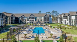 A hotel with a central swimming pool, outdoor seating, and a well-maintained lawn. - Landing | Modern 1BD, Courtyard, Gym (Mobile)