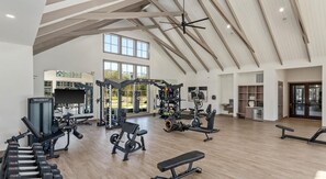 Une salle de sport spacieuse, dotée de divers appareils d’exercice, de grandes fenêtres et d’un plafond haut.