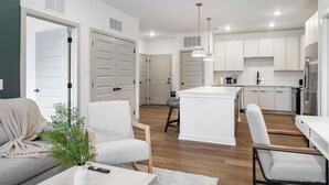 Una cocina moderna con armarios blancos, una isla central e iluminación colgante.