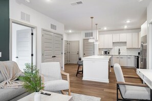 A modern kitchen with white cabinetry, a central island, and pendant lighting.