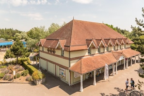 A building with a tiled roof, a covered entrance, and a landscaped garden area. - Retreat Near the Baie de Somme (Fort-Mahon-Plage)
