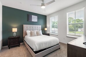 Une chambre à coucher avec un lit, des tables de chevet, un ventilateur de plafond et des fenêtres.