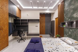 A bedroom with a bed, desk, chair, wardrobe, and built-in shelving.