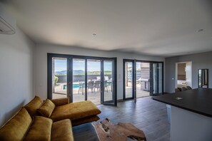 Una sala de estar moderna con un sofá, una mesa de centro de madera y una zona de cocina con mostrador.