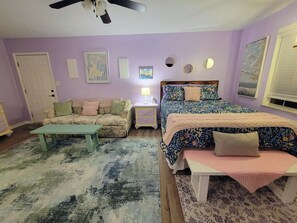 A bedroom with a bed, a nightstand, a dresser, a sofa, a coffee table, and a ceiling fan.