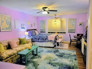 A bedroom with a bed, a sofa, a desk, and a chair.