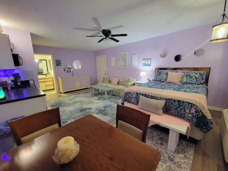 A bedroom with a bed, a desk, a chair, a ceiling fan, and a dining table.. Enjoy a 1 bedroom 1 bath cottage on the green at Perdido Bay Country Club.