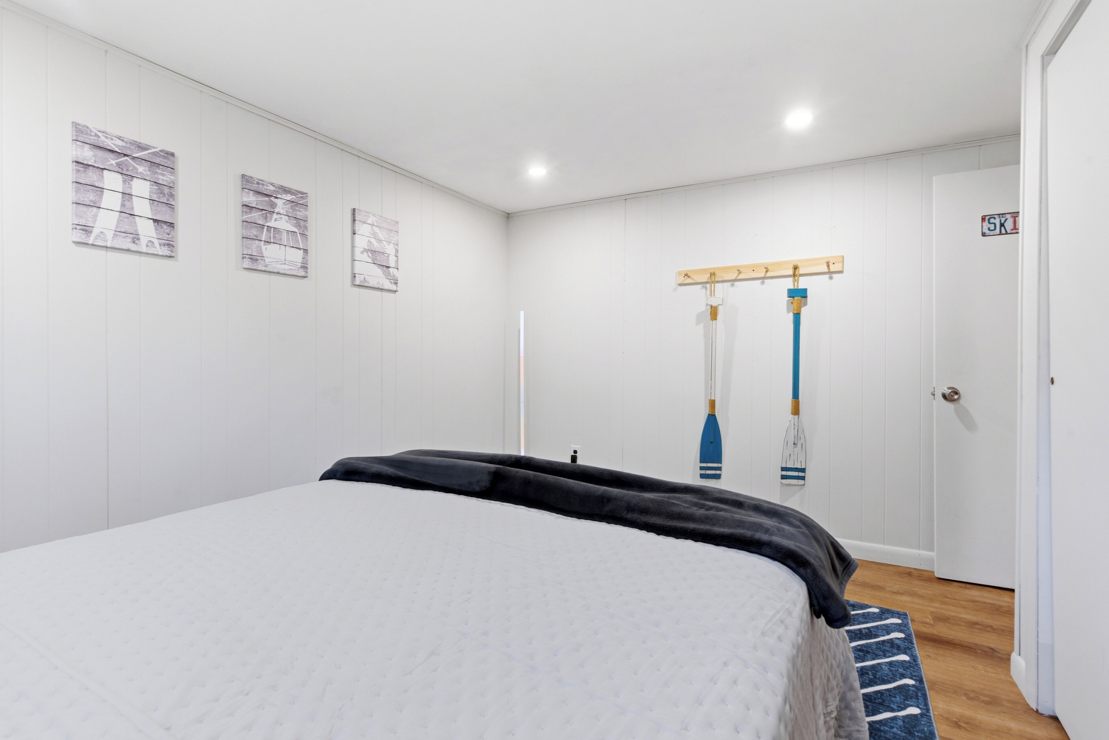 A bedroom with a bed, a wooden door, and a wall-mounted rack with items.