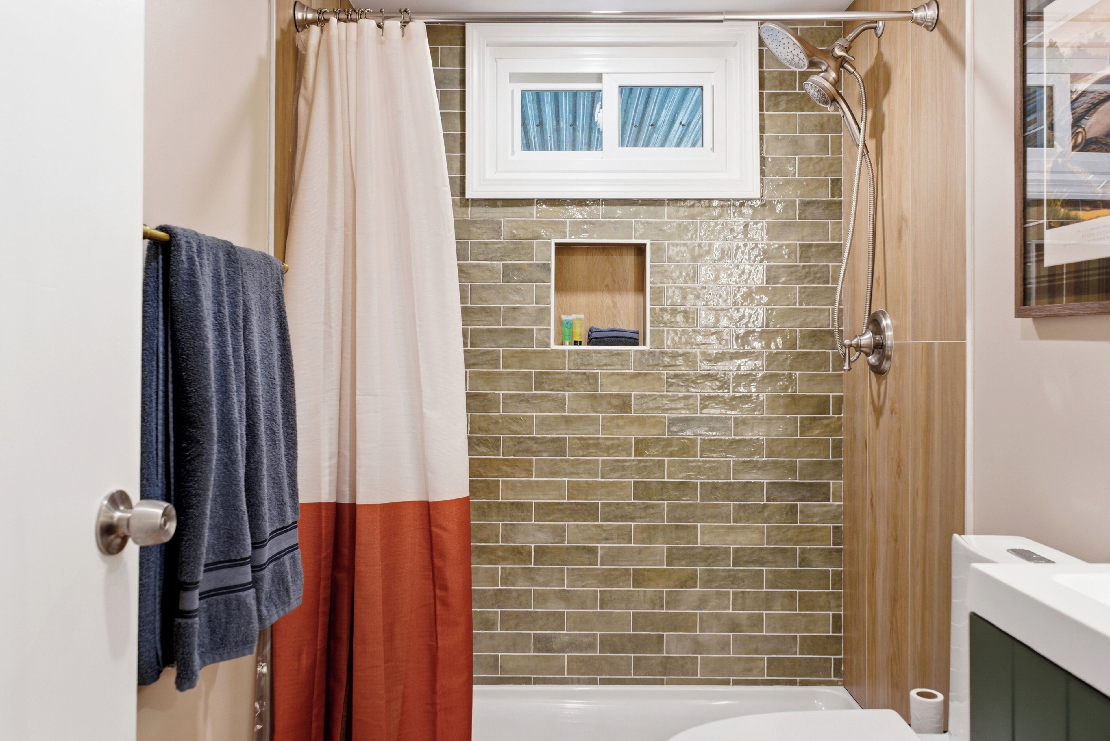 A bathroom with a shower, a towel rack, a toilet, and a small shelf with toiletries.
