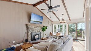 Una sala de estar con chimenea, un sofá, un televisor y un comedor con vistas.