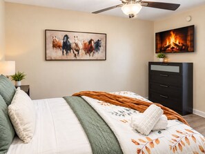 A bedroom with a bed, a ceiling fan, a fireplace, a dresser, and a painting on the wall. - Modern 1BR near Downtown TPA and Raymond James Stadium (Tampa)