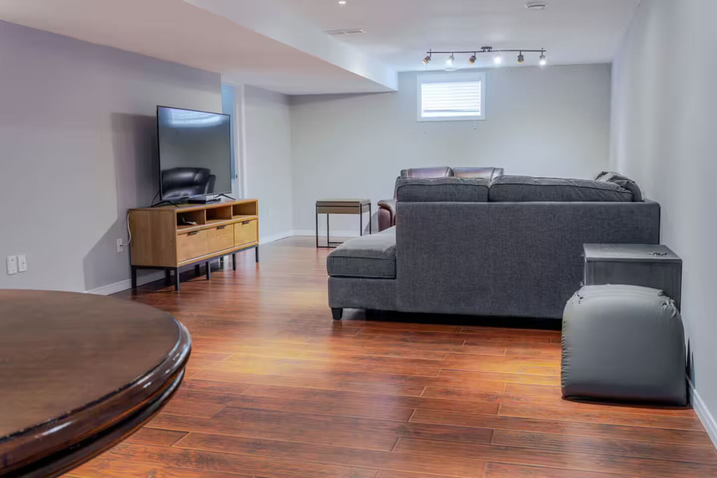 Un salon moderne avec un canapé, un téléviseur, un meuble en bois et une petite table.